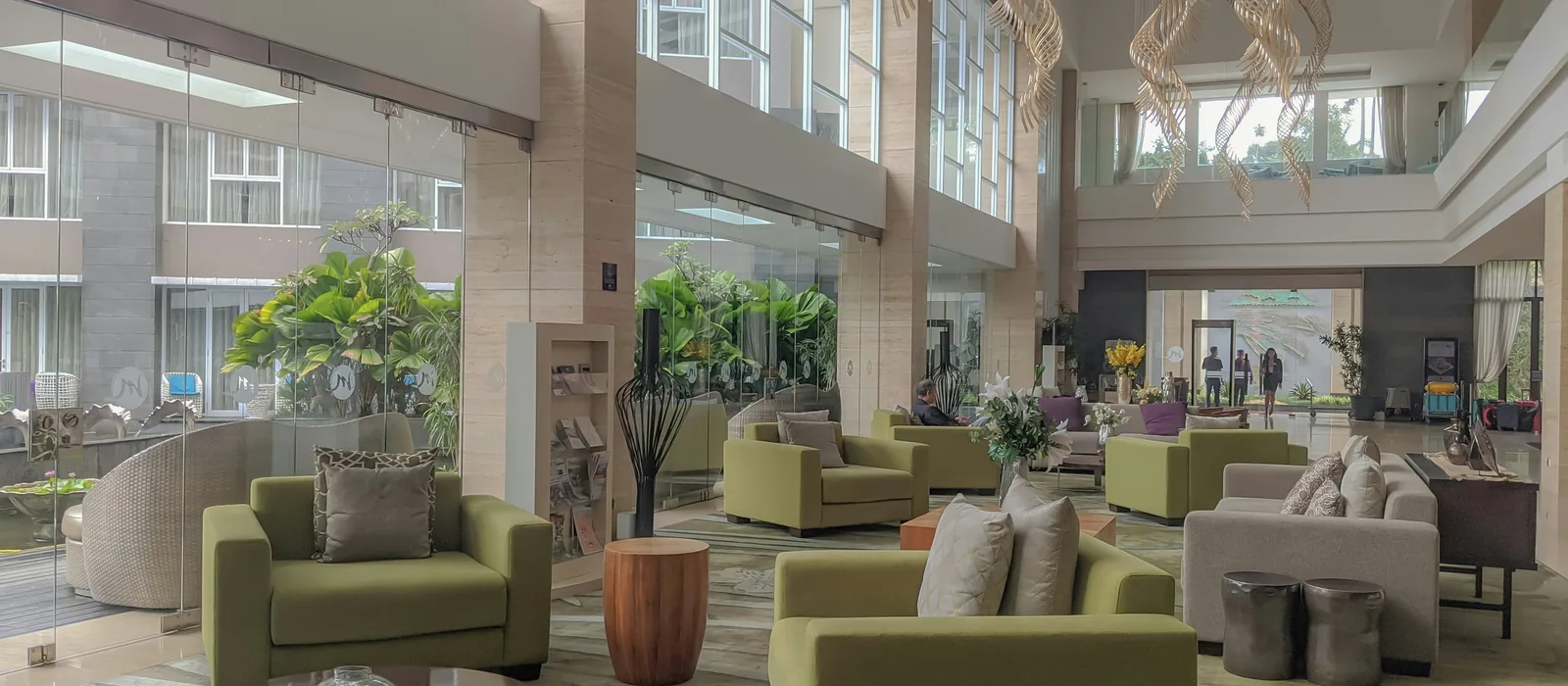 Átrio amplo e iluminado de hotel com poltronas verdes