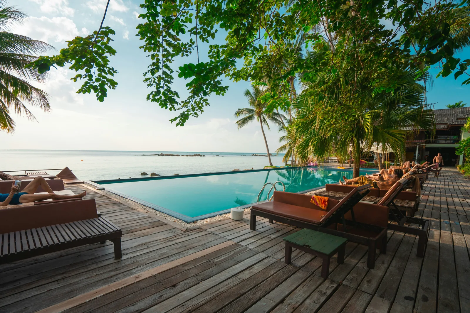 Deque de piscina de resort tropical com espreguiçadeiras e coqueiros
